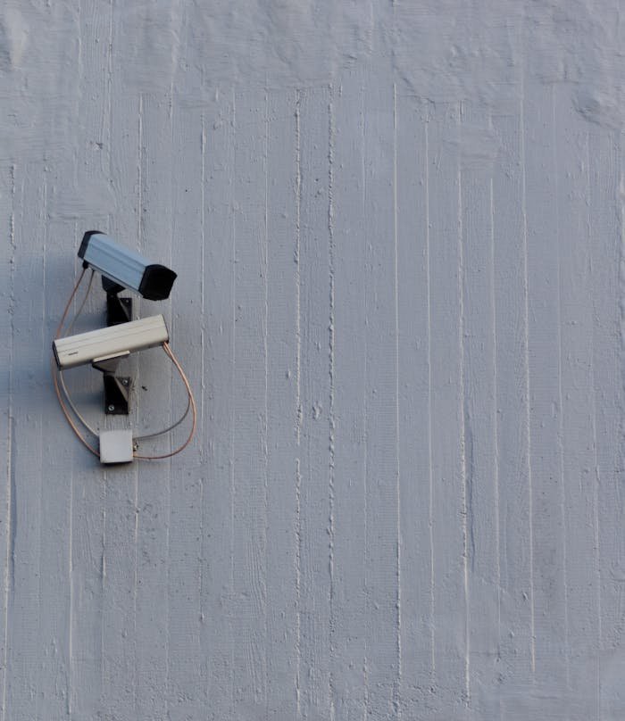 Two surveillance cameras mounted on a wall for security and safety monitoring.